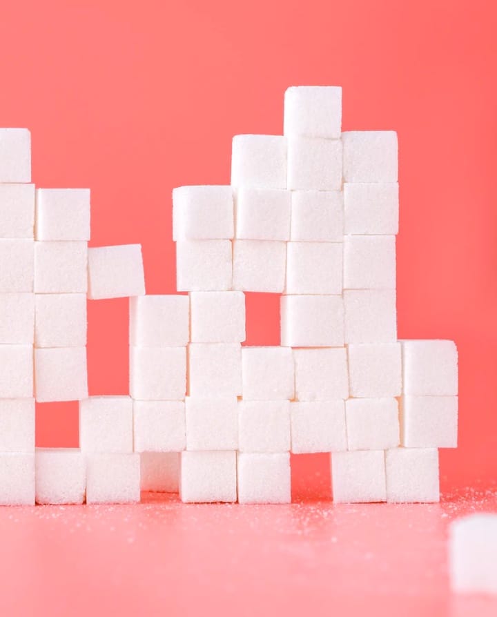 picture of sugar cubes stacked on another on a light red color background