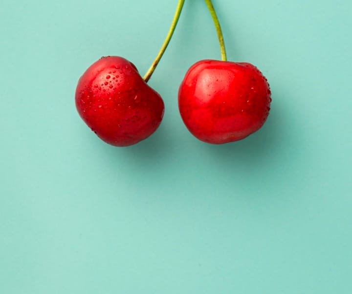 Picture of two cherries on a light green background