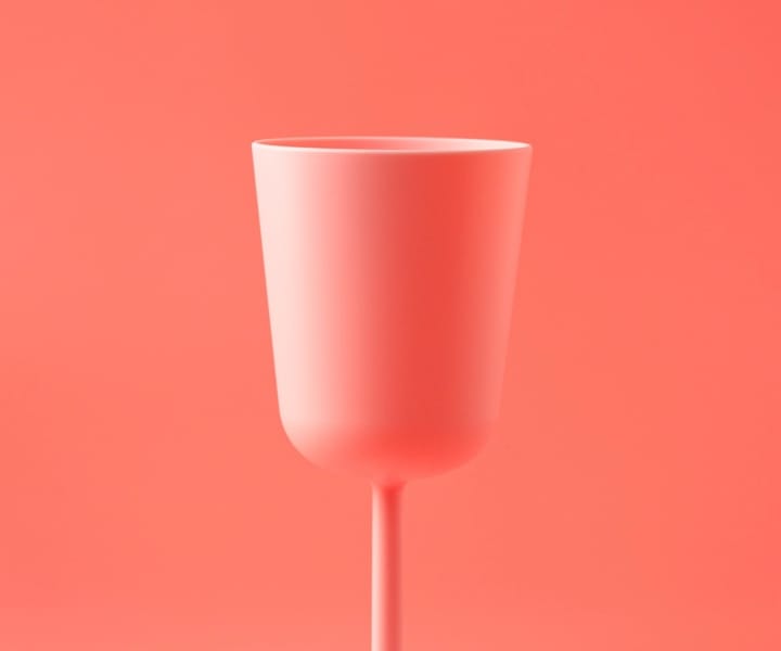 picture of a light red colored matte finish wine glass on a light red color background